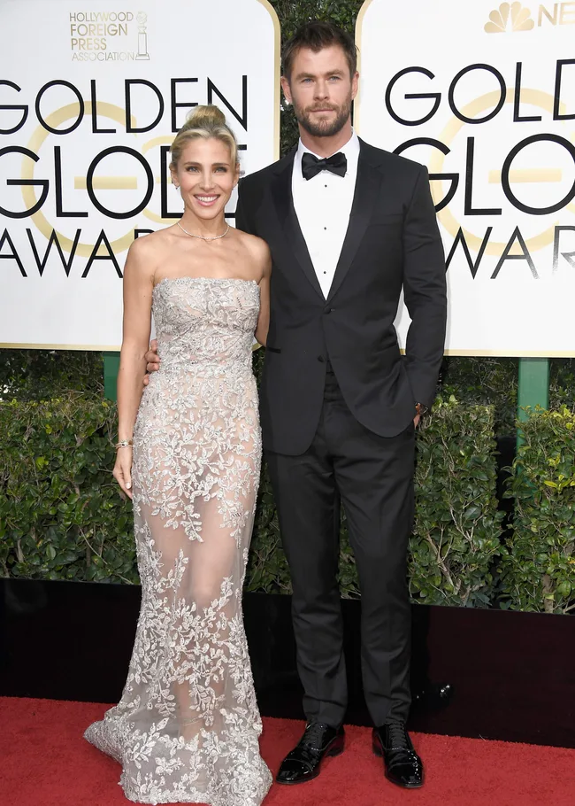 Couple posing on the red carpet at the Golden Globe Awards, dressed in formal attire.