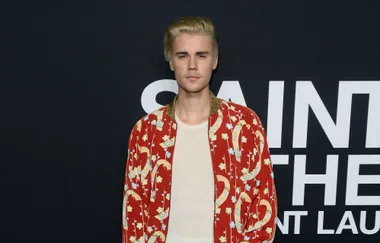 Person in a red floral jacket, standing against a black background with white text.