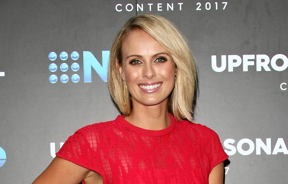 A woman in a red dress smiles at a 2017 media event.