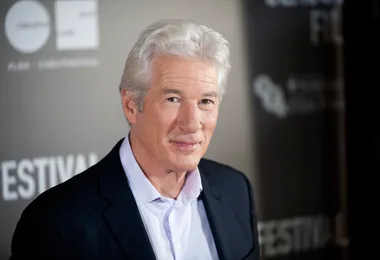 ```plaintext
A man with gray hair in a suit smiles at a film festival event.
```