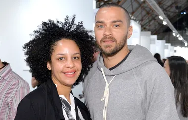 A man and woman smiling at an indoor event, with people in the background.