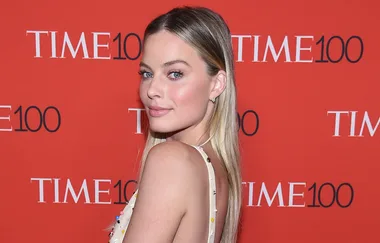 A woman at the TIME 100 event, posing in front of a red backdrop with the logo.