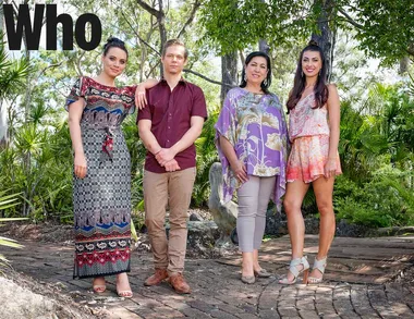 Group of four people posing outdoors among trees and greenery.