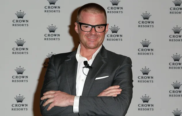 Man in a suit with glasses smiling, standing in front of a Crown Resorts backdrop.