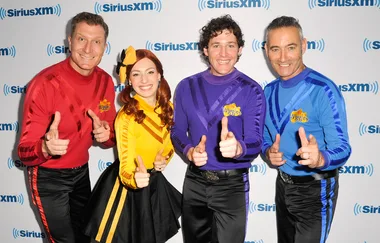 Four people in colorful uniforms posing with thumbs up in front of a SiriusXM backdrop.