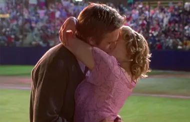 Couple kissing passionately at a crowded baseball stadium.
