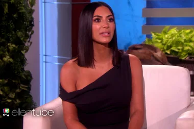 Person with long dark hair in a black one-shoulder dress, sitting on a white couch, with "ellentube" logo in frame.