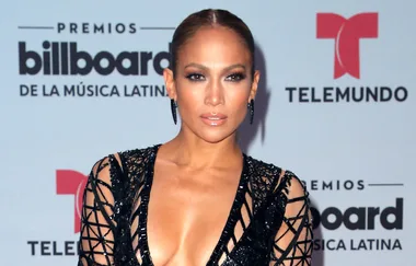 Person in an elegant black dress at the Billboard Latin Music Awards with a step and repeat backdrop.
