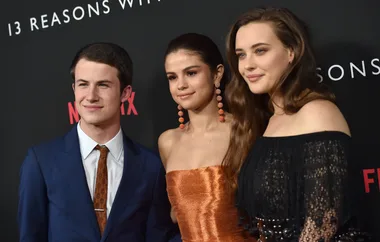 Three people pose at the "13 Reasons Why" event, dressed formally with a backdrop of the show's title and Netflix logo.