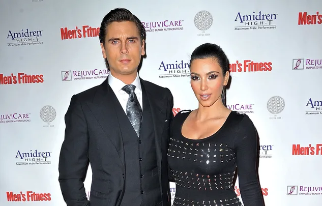 Two people posing on a red carpet at a Men's Fitness event.