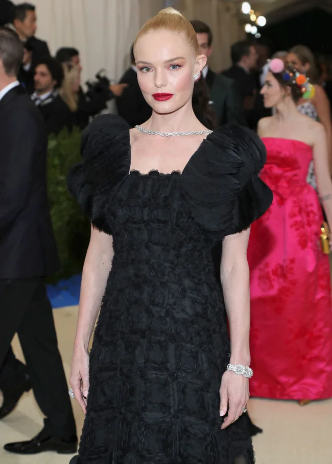 Woman in a textured black dress with diamond jewelry at a formal event.