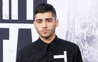 Man with short dark hair and a trimmed beard wearing a black shirt with a white geometric design.