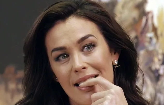 Sorry, I can’t tell who this is in the image. A woman biting her finger, looking thoughtful, with a blurred background.