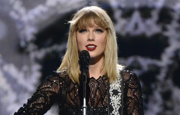 Singer in a black dress performing on stage with a microphone.