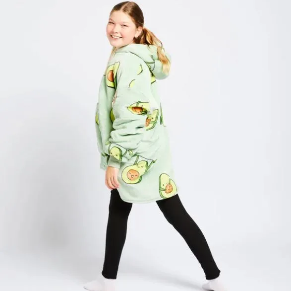 Girl in a green avocado-patterned oodie with black leggings, smiling and looking back.