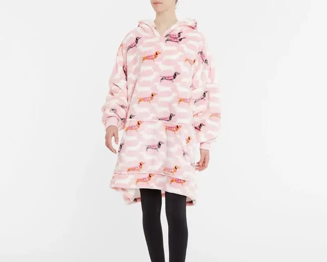 Young person wearing a pink, oversized hooded blanket with dachshund print, paired with black leggings.