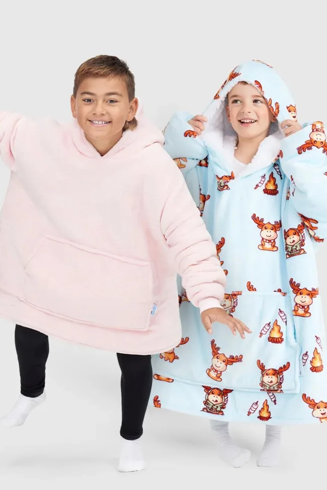 Two smiling kids wearing oversized hooded blankets. One in pink and the other in blue with campfire print.