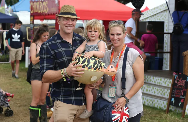 A family poses happily at an outdoor festival, holding an inflatable turtle toy.