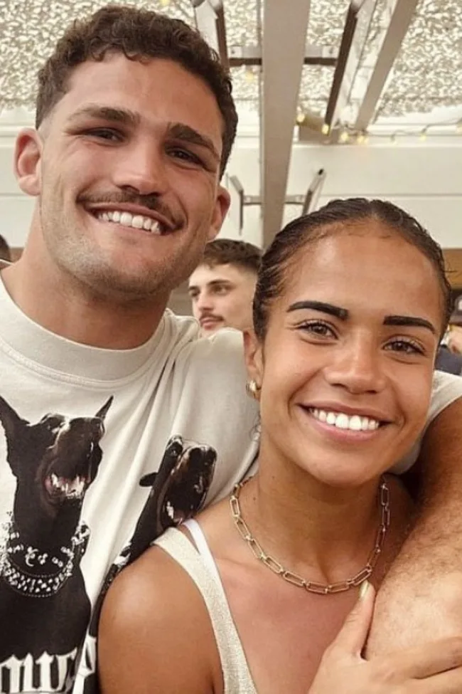 Two people smiling, standing close together in a well-lit room with decorations on the ceiling.