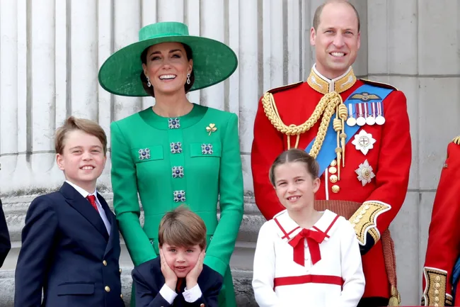 A smiling family in formal attire; woman in green, man in uniform with kids in suits and dress.