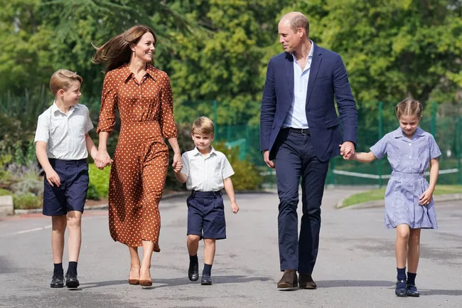 Family walking together outdoors, holding hands, dressed in casual smart attire on a sunny day.