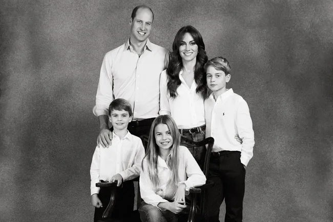 A family of five in matching white shirts poses together in a black and white portrait.