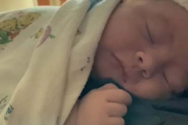A newborn baby wrapped in a blanket, peacefully sleeping.
