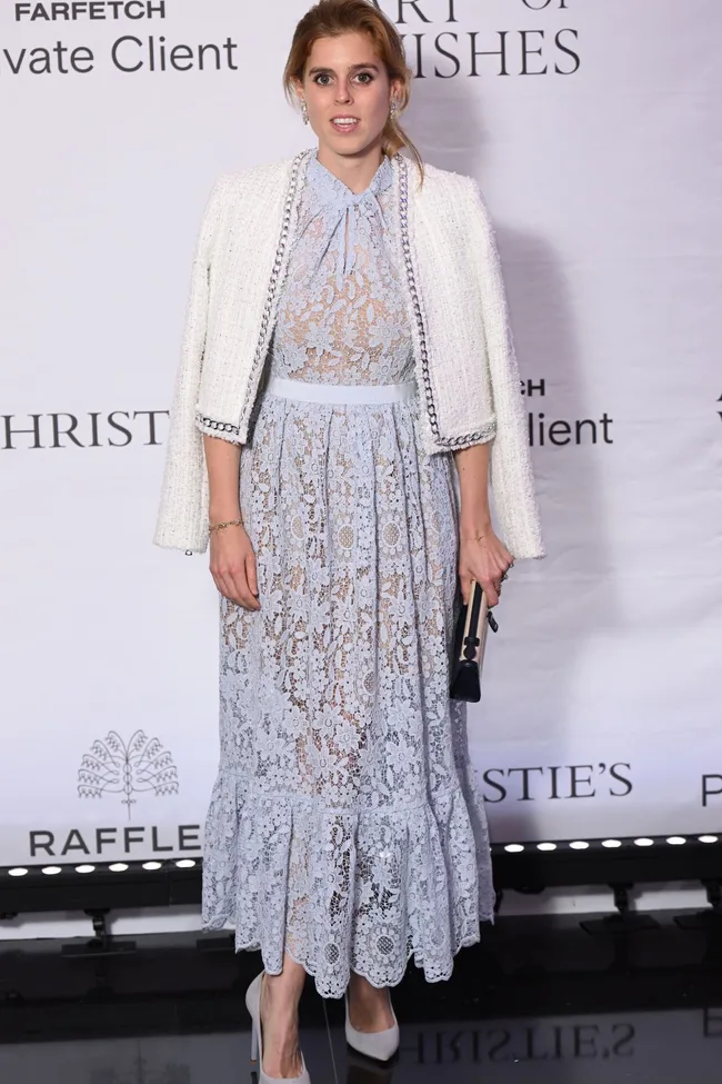 Princess Beatrice in a blue lace dress and white blazer, holding a clutch at a formal event.