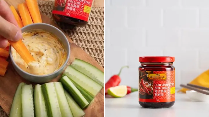 Carrot dipped in spicy mayo near cucumber; Lee Kum Kee Chili Oil jar and chili peppers on white background.
