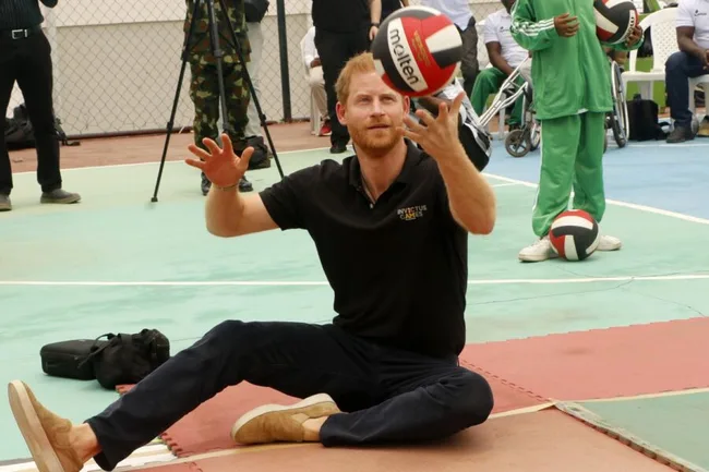 Prince playing seated volleyball on a court, wearing a black Invictus Games polo shirt.