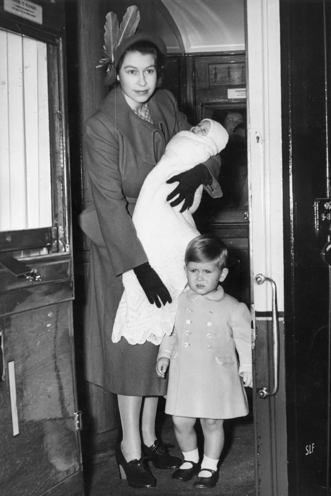 queen elizabeth hold baby princess anne in her arms as king charles walks in front