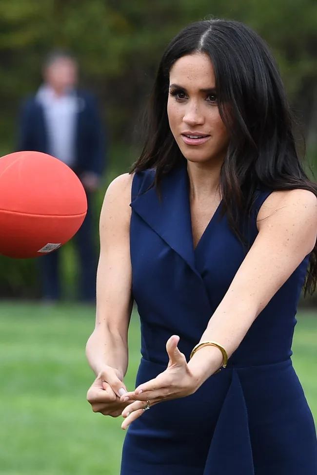 Woman in navy dress catching a red ball outdoors.