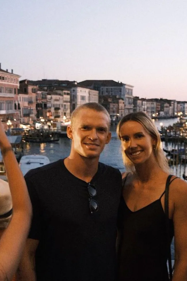 Couple smiling at the camera with a canal view in the background.
