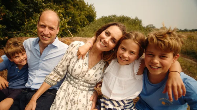 "Family sitting together outdoors, smiling at the camera."