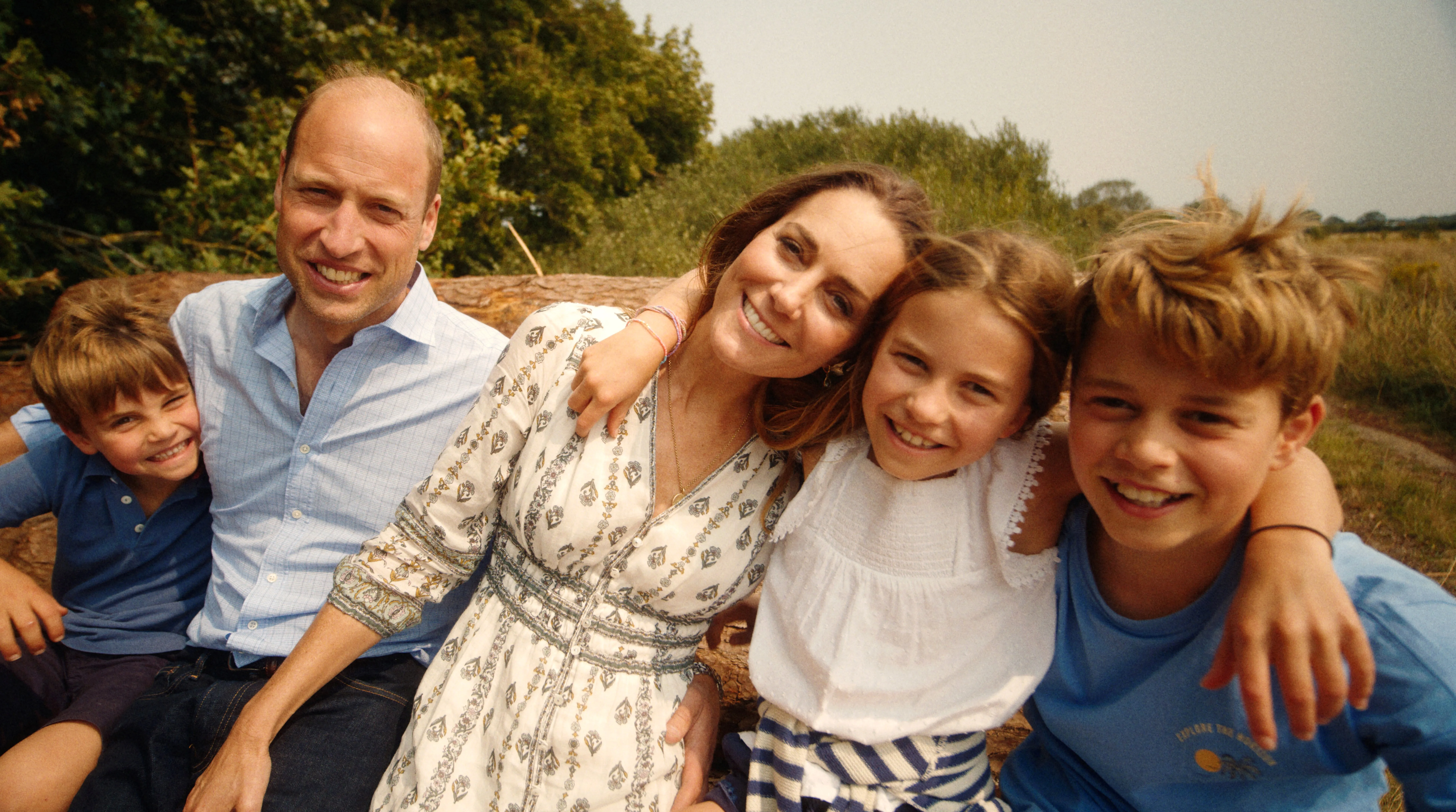 "Family sitting together outdoors, smiling at the camera."