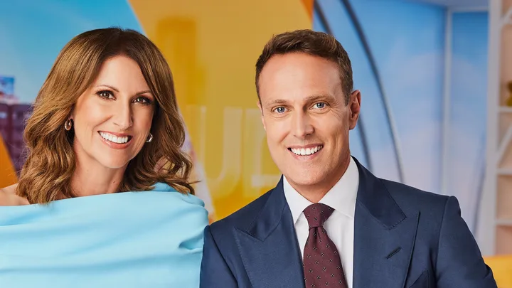 Two smiling people in formal attire with a colorful background.