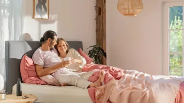 stock couple sharing a coffee in bed on an emma sleep mattress
