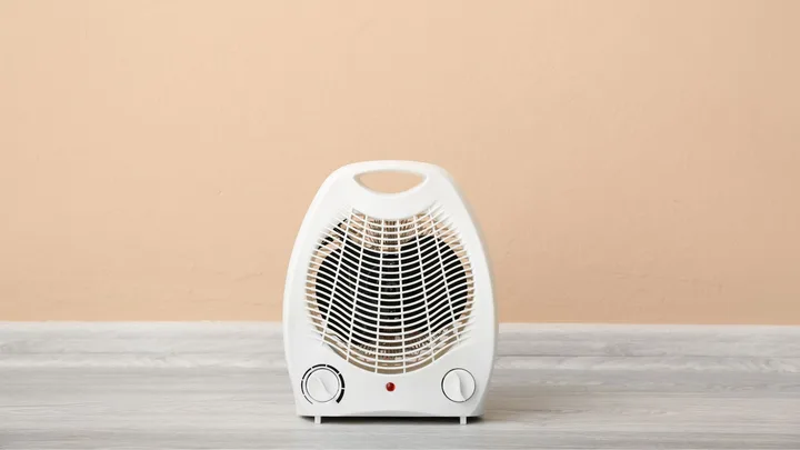 white fan heater on table with peach background