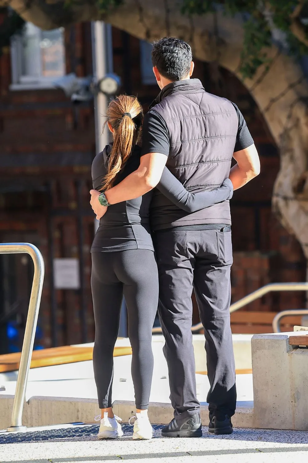 ada nicodemou and james stewart stand with their back to the camera as they cuddle eachother side by side