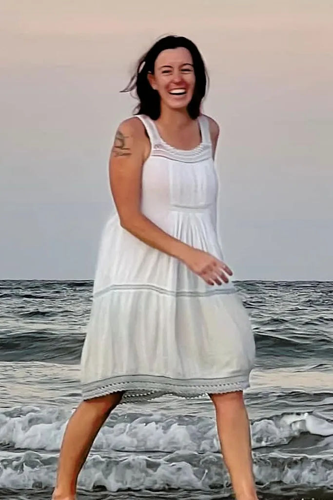 natasha ryan walking on the beach in a white dress