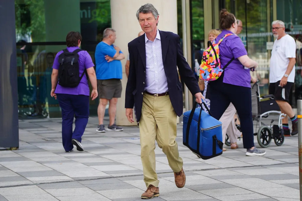 princess anne's husband sir timothy laurence leaves the hospital as he hold a blue cooler bag in his hand