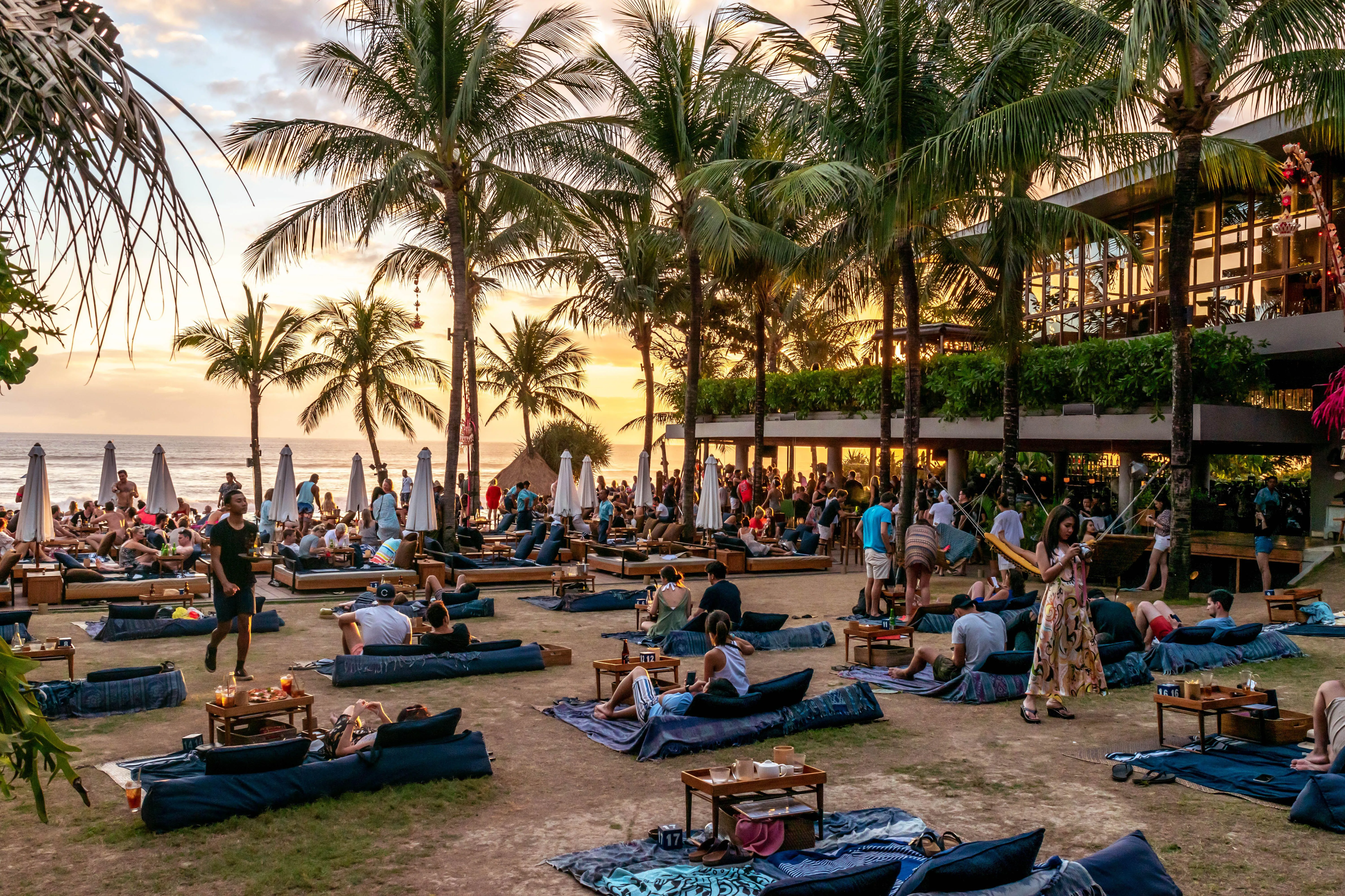 2C567YR Seminyak, Bali / Indonesia - September 09 2018: Australian tourists enjoy drinks and watch a warm sunset at the world famous Potato Head Beach Club.