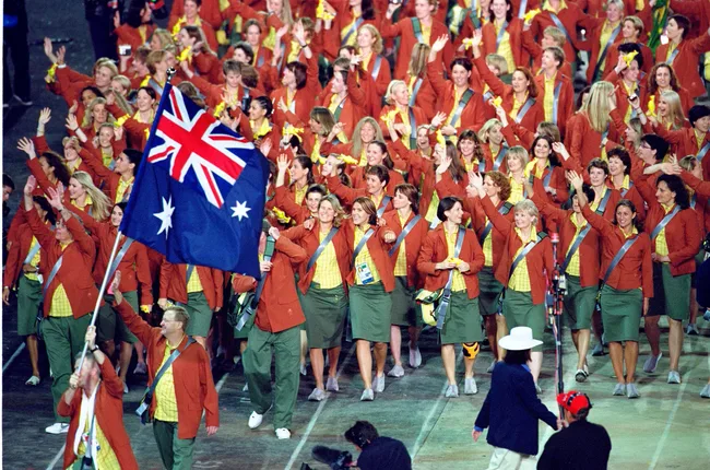 Australian Olympic team marching with flag, dressed in red blazers and green skirts at the 2000 Sydney Olympics opening.