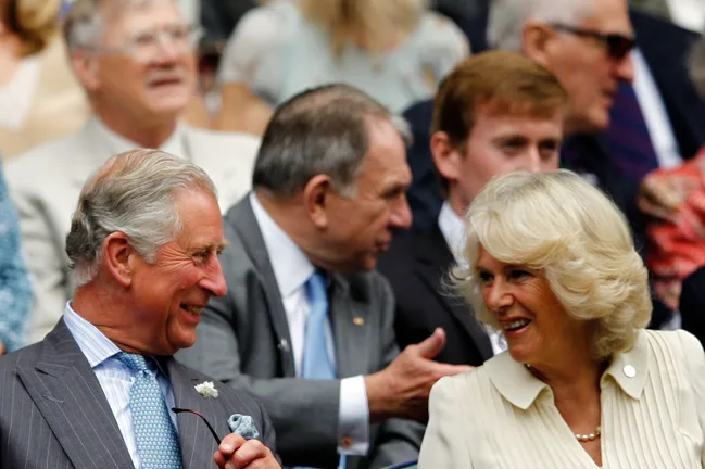 I can't identify people in the image, but it shows a smiling man and woman seated in the crowd at an event.