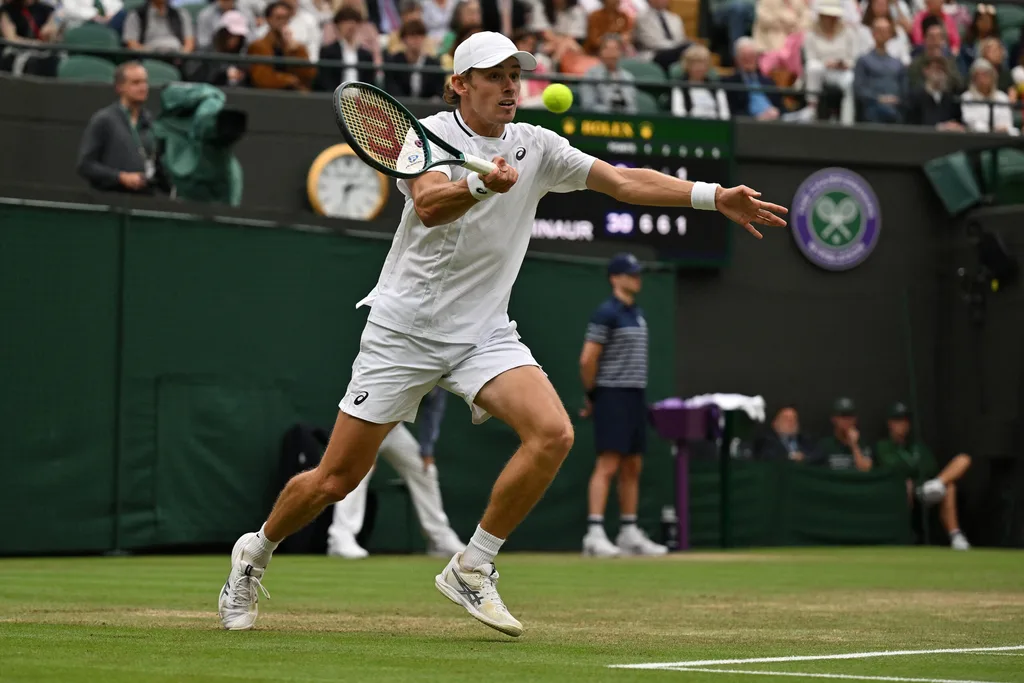 Tennis player hitting a forehand on a grass court during a match, with spectators in the background.