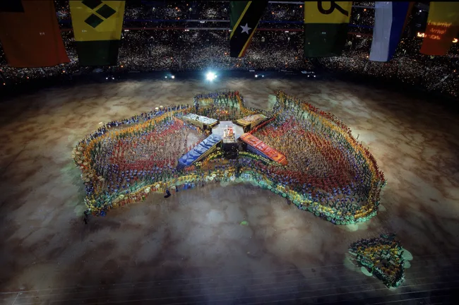 Crowds in colorful formations resemble Australia at the 2000 Sydney Olympics opening ceremony.
