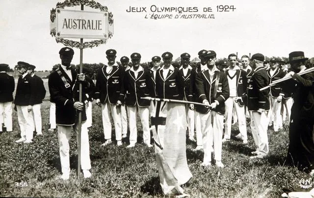 Australian team at the 1924 Olympics, wearing blazers and hats, holding a sign "Australie." Black and white photo.