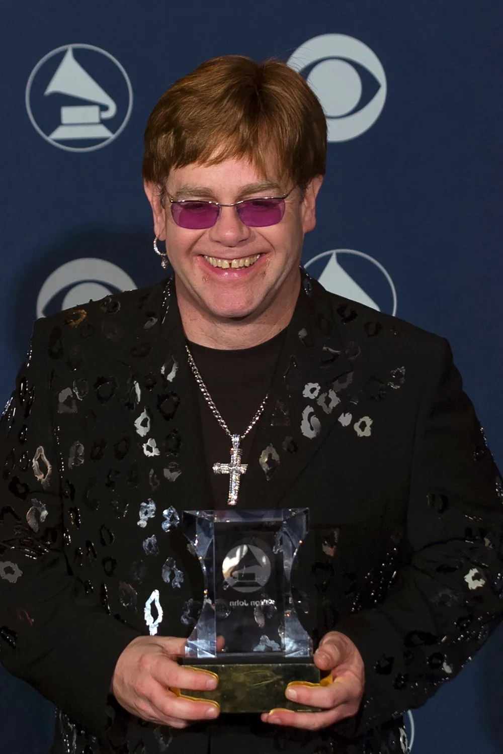 eton john wearing purple sunglasses holding his grammy at the annual grammy awards in 2000.