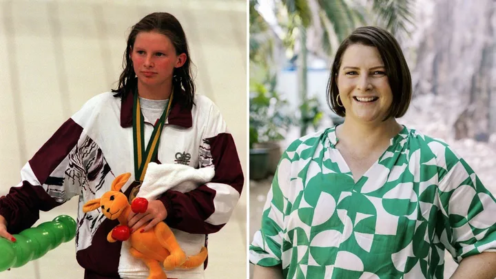A young woman in a sports jacket holding a medal and toy, next to her smiling in a green patterned dress.