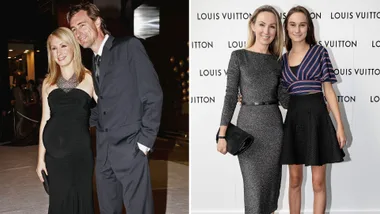A pregnant woman in a black dress with a man in a suit, and two women posing at a Louis Vuitton event.